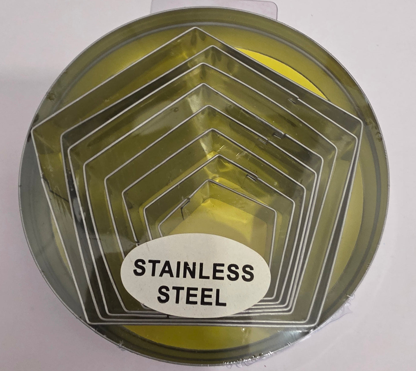 A set of stainless-steel hexagon cutters in various sizes, stored inside a round metal tin with a lid.