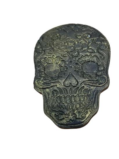 A gold-colored cake decorating piece shaped like a skull with intricate details.