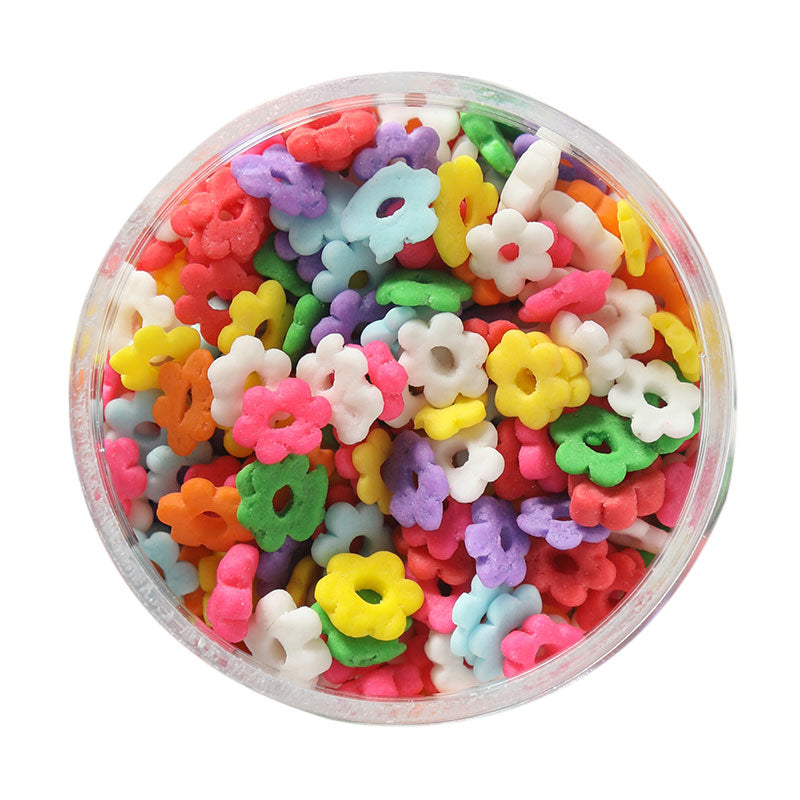 A clear container filled with colorful flower-shaped sprinkles for cake decoration.
