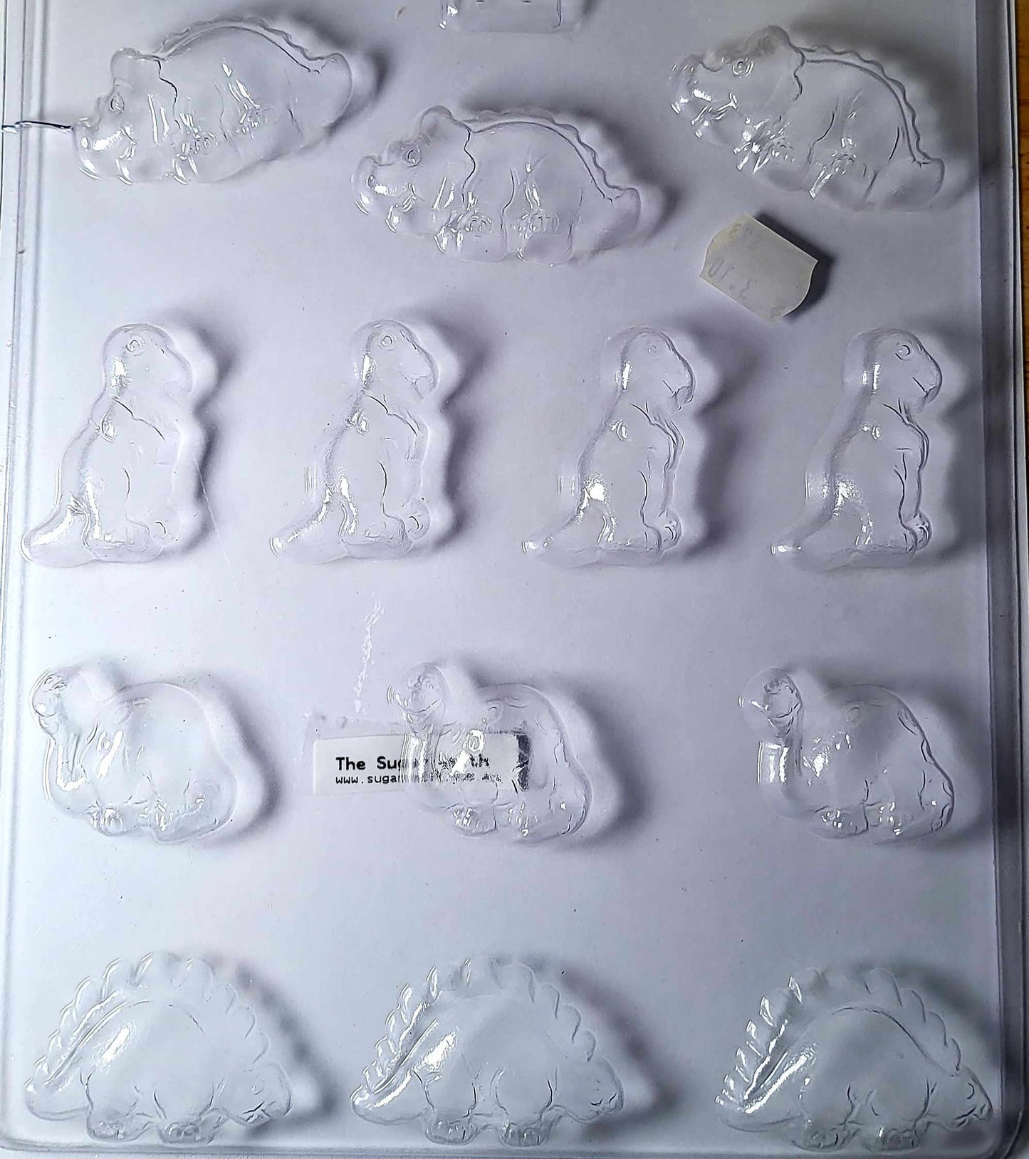 A set of clear plastic dinosaur-shaped chocolate moulds with various dinosaur designs including a triceratops.