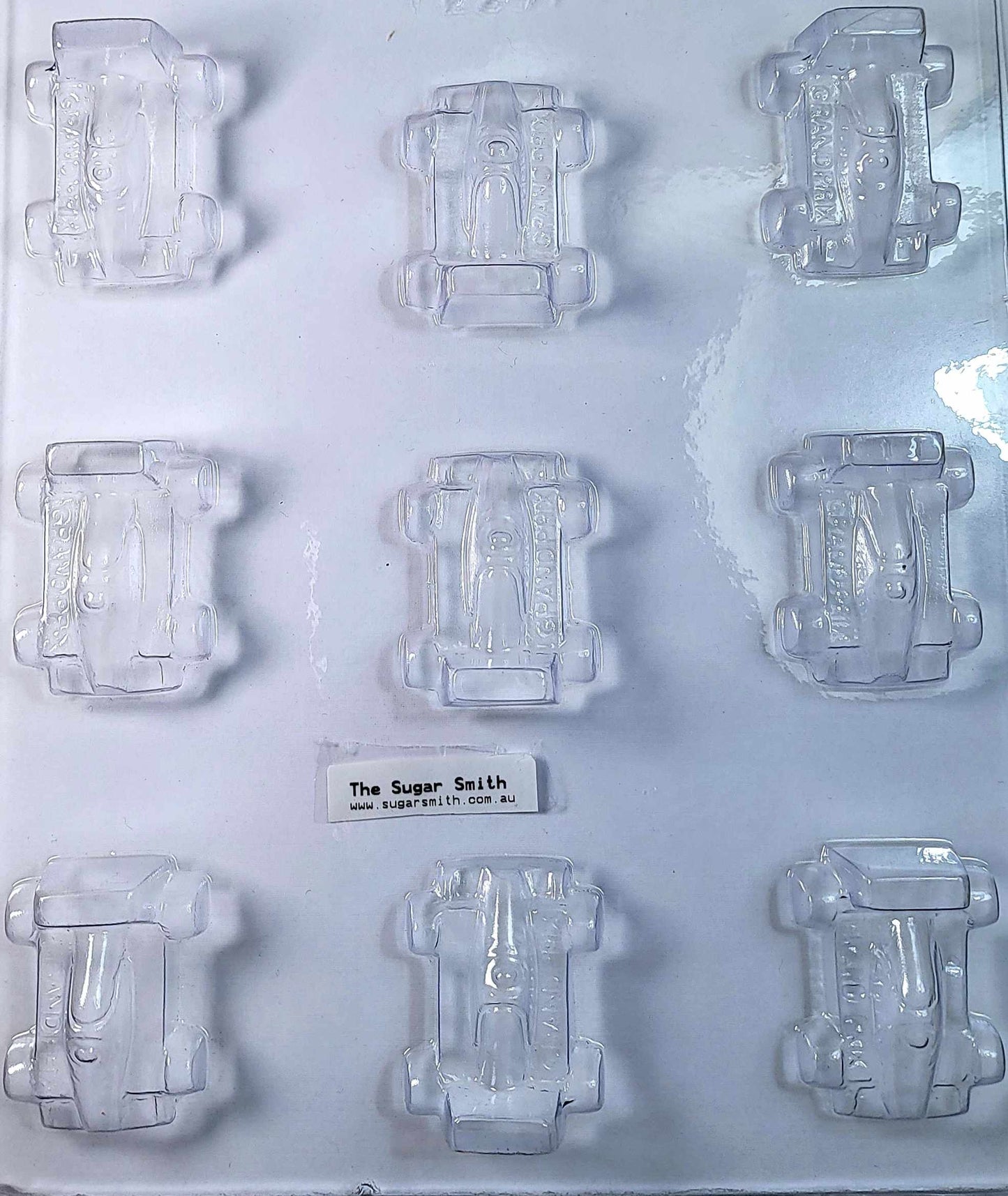 A clear plastic chocolate mould designed to shape nine grand prix-style cars.