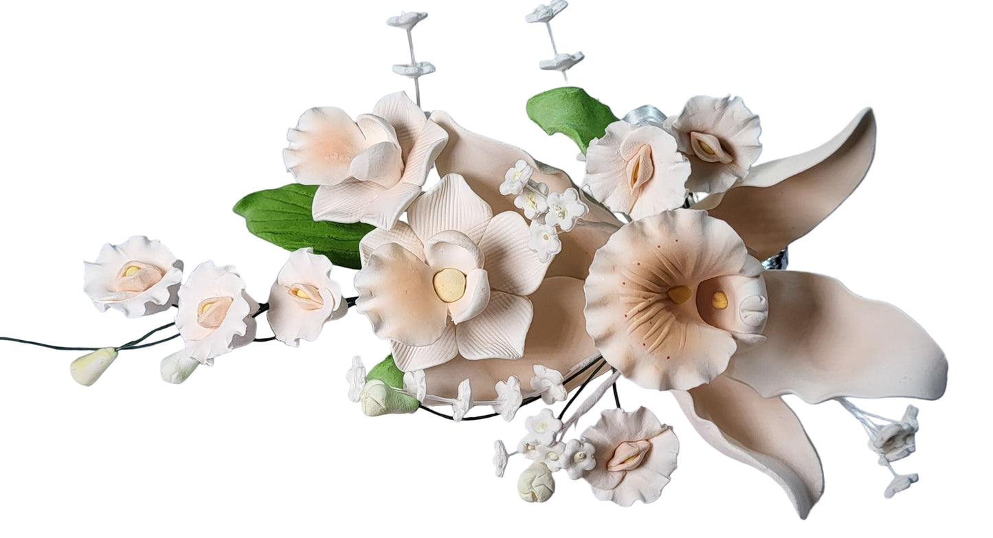 A peach/apricot cymbidium orchid spray with white fillers, green leaves, and sweet peas designed for cake decoration.