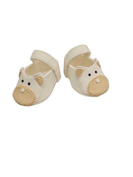 Pair of cream-colored baby shoes with bear face design on a white background