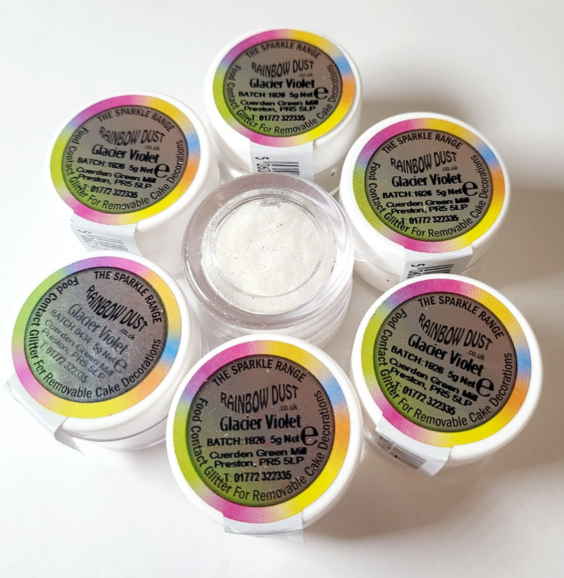 Small 5g pot of Rainbow Dust Glacier Violet, showing a fine multicoloured shimmer. The glitter has a soft violet tone with iridescent sparkle, used for adding shine to removable cake decorations.