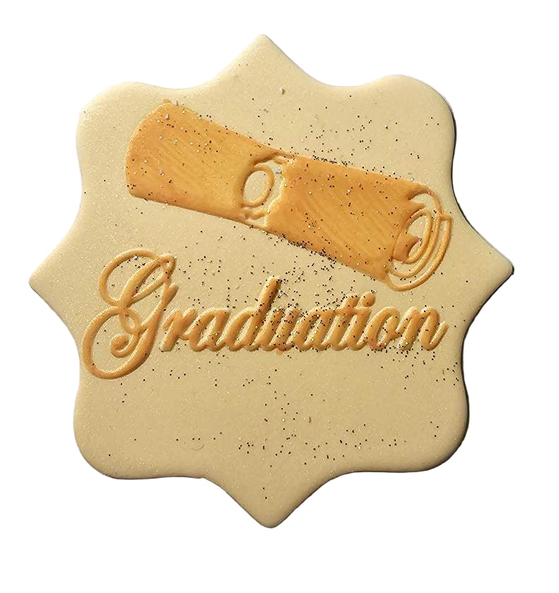 A gold-colored, icing-based graduation plaque with the word 'GRADUATION' embossed on it, along with a decorative scroll.