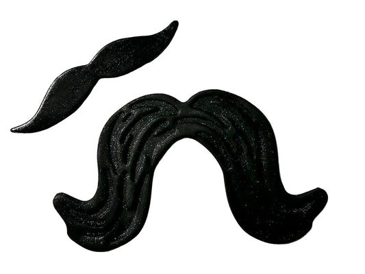 Two black icing decorations shaped like moustaches, one large and one small, on a white background.