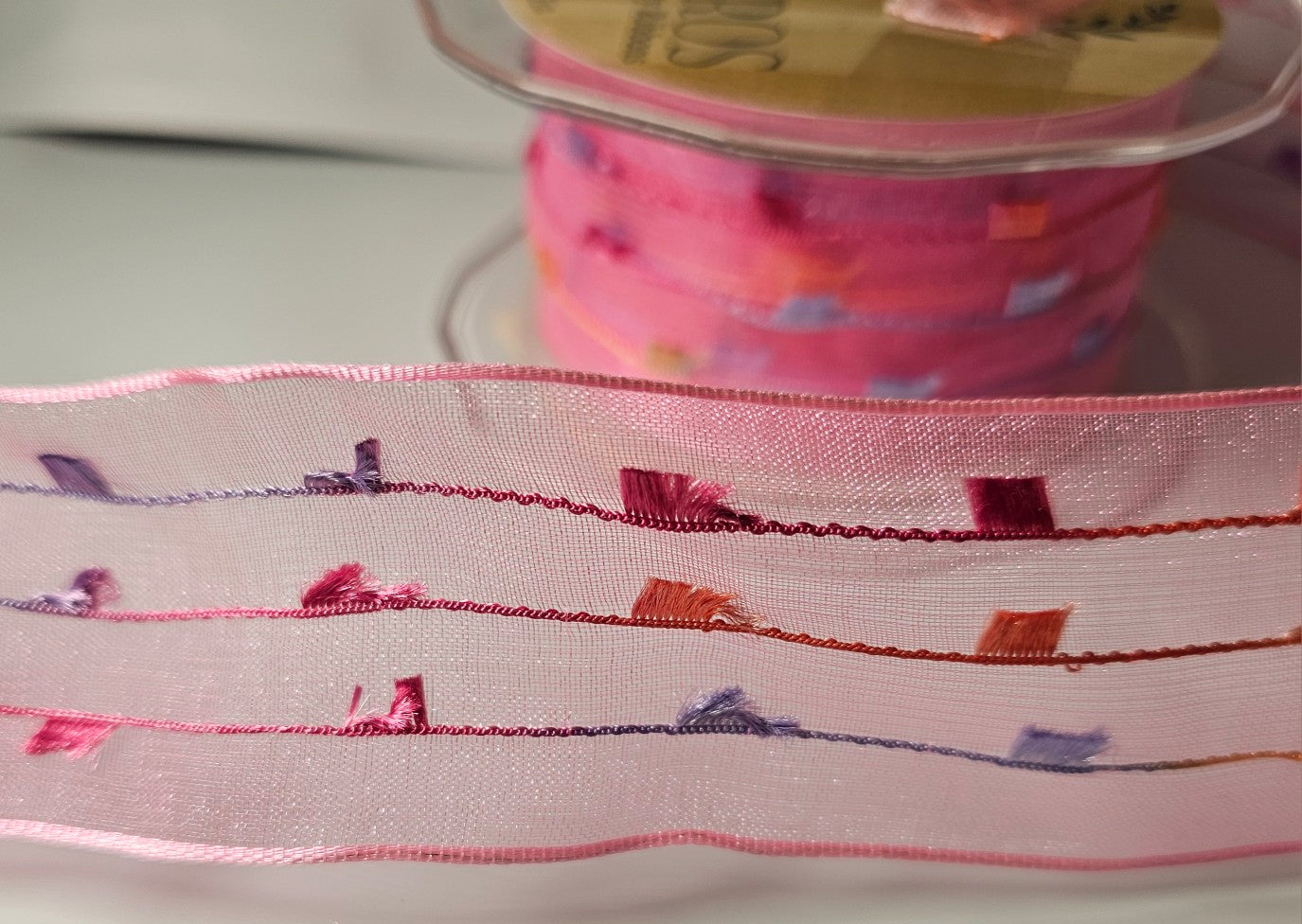 Sheer Pink Ribbon with Solid Magenta Pink, Lilac and Orange line and Tassels Close Up.
