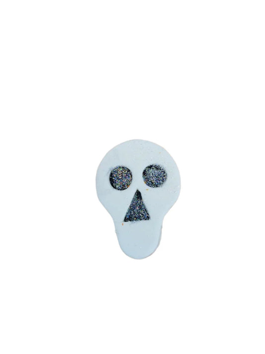 A small, handcrafted sugar skull with glitter eyes and mouth, intended for decorating cakes and cupcakes.