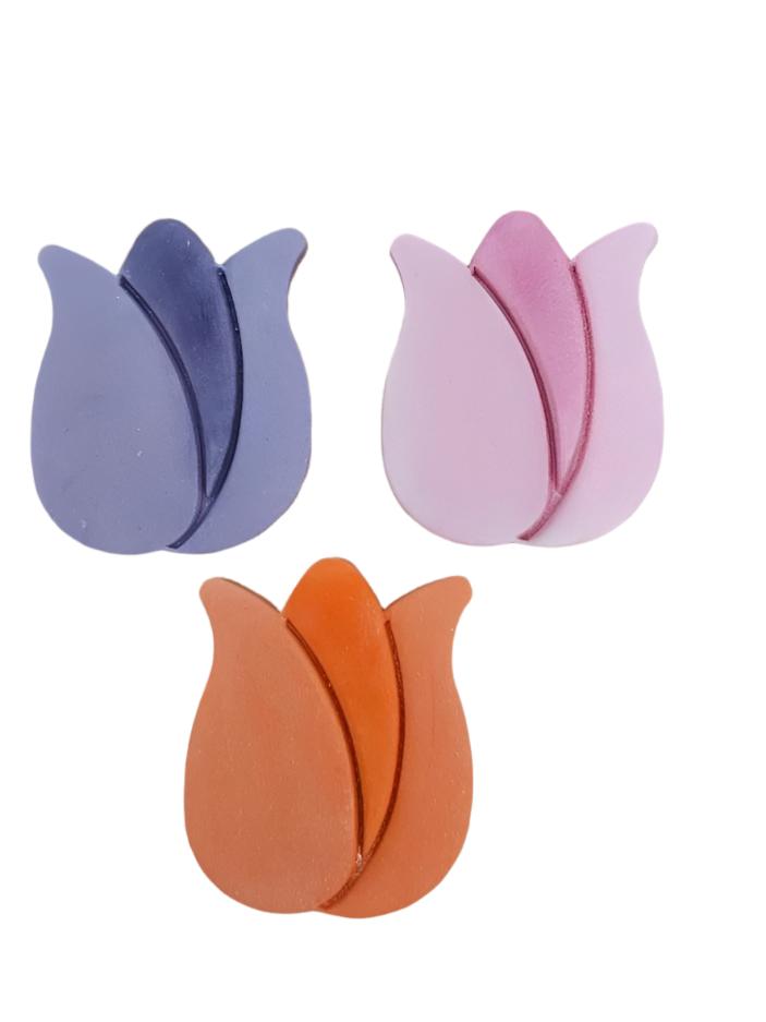 A set of three icing tulip decorations in pink, purple, and orange colors.