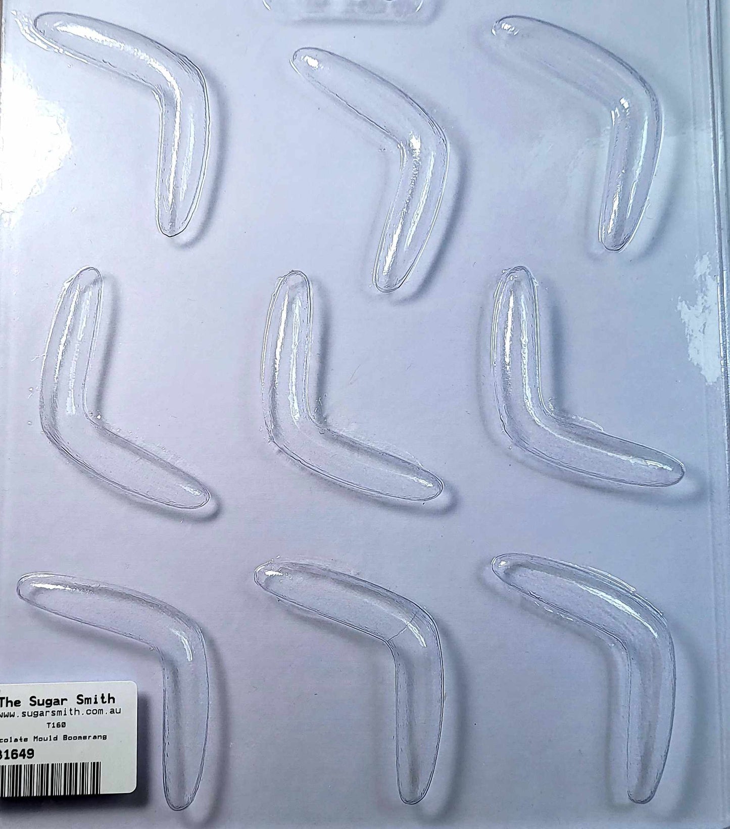 A clear plastic chocolate mould with 9 cavities, arranged in a boomerang shape, packaged on a white background with a label at the bottom.
