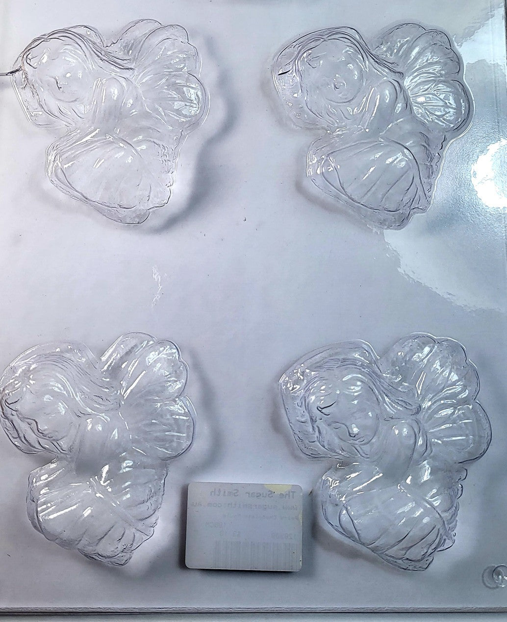 A clear plastic chocolate mould designed to create fairy-like figures, with intricate detailing.