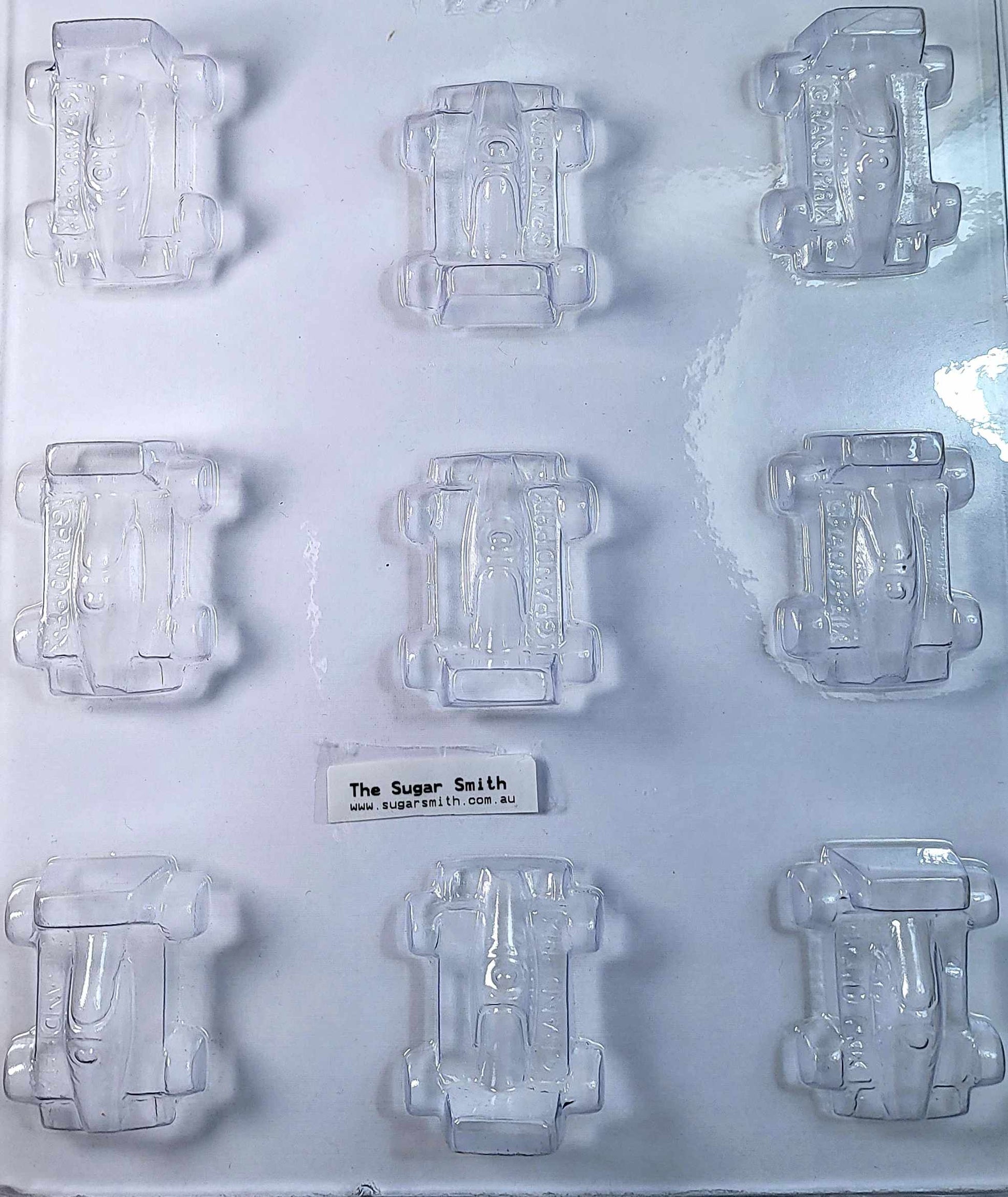 A clear plastic chocolate mould designed to shape nine grand prix-style cars.