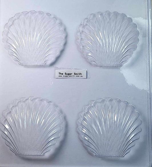 A clear, four-cavity chocolate mould in the shape of a clam shell.