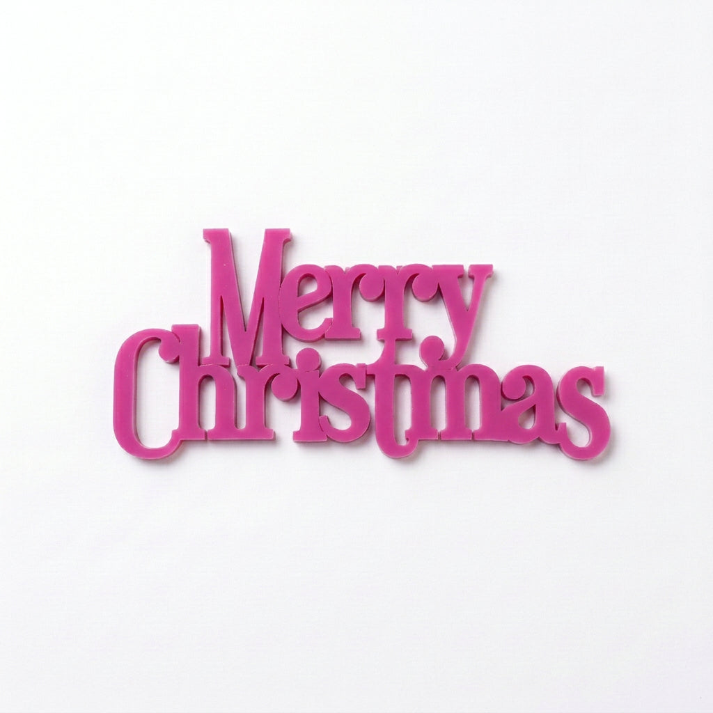 Large plastic Merry Christmas cake plaques in bright magenta, measuring approximately 13.8cm wide by 6.2cm high.