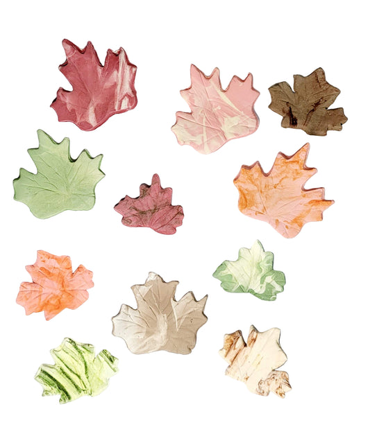 A collection of edible autumn-colored icing leaves in various shades of orange, brown, and green, suitable for cake decoration.